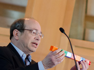 نیل آرونین از بلوک‌های بزرگ لگو برای توضیح این که چگونه داروهای خاموش‌سازی ژن ممکن است به مولکول‌های کوچک‌تری با عوارض جانبی خاص خود تجزیه شوند، استفاده می‌کند. اعتبار تصویر: Lev Blumenstein برای CHDI   